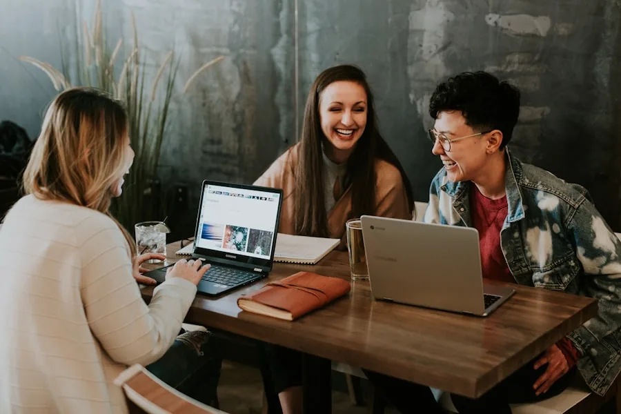 Three people talking together around a table with laptops
